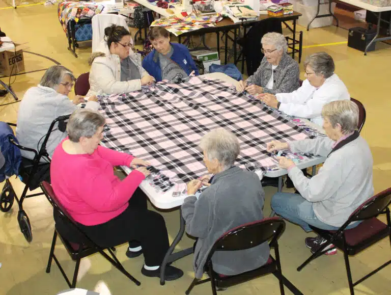 Cathy and Iris, at the top of the table, came from Commonwealth Connections to help speed the blanket making on March 11. The Sisters clockwise around the table starting at right are Sister Ann Patrice Cecil, Sister Margaret Ann Aull, Sister Maureen O’Neill, Sister Joan Riedley, Sister Rose Jean Powers and Sister Mimi Ballard. Sister Mimi said the women she works with in Chile make lap blankets for the elderly in a similar way. Cathy and Iris, at the top of the table, came from Commonwealth Connections to help speed the blanket making on March 11. The Sisters clockwise around the table starting at right are Sister Ann Patrice Cecil, Sister Margaret Ann Aull, Sister Maureen O’Neill, Sister Joan Riedley, Sister Rose Jean Powers and Sister Mimi Ballard. Sister Mimi said the women she works with in Chile make lap blankets for the elderly in a similar way.