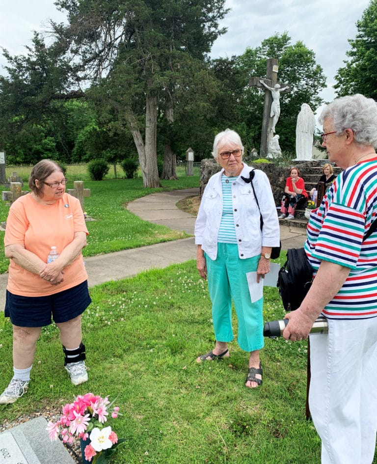 Associate Pam Knudson, left, Associate Janice Arth, center, and Sister Michele Morek visit at the grave of Sister Mildred Katzer, the last Ursuline buried in the cemetery in 2019.