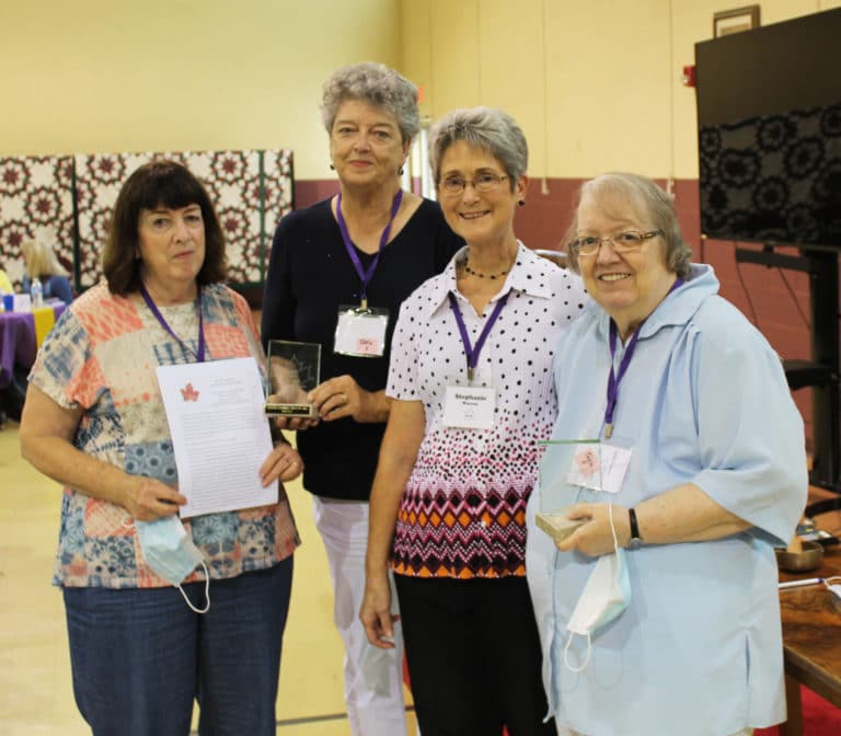 The Costello sisters, Phyllis Costello Bresnik, A66, left, and Mary Costello, A65, right, accept their Maple Leaf Awards, along with one of their nominators, Cecilia Robinette McEldowney, A66, second from left, and Stephanie Warren, Alumnae Association president.