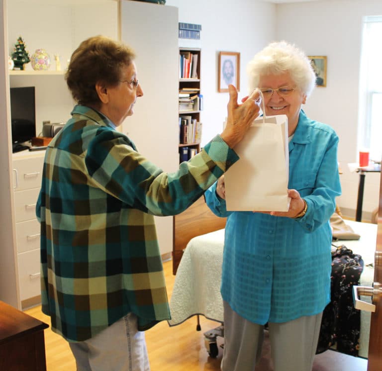 Sister Francis Louise Johnson, right, smiles as Sister Susan Mary Mudd hands her a goody bag.