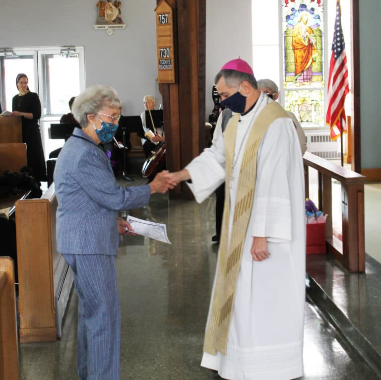 Sister Elaine Burke shakes hands with Bishop Medley and receives a certificate and gift. Sister Elaine celebrated 70 years in 2020.