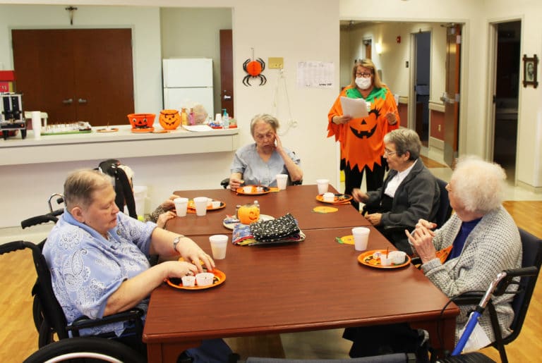 Activity coordinator Debbie Dugger, dressed as a pumpkin, shares some tidbits about Halloween while the Sisters enjoy their treats. From left are Sisters Kathleen Dueber, Marie Julie Fecher, Kathy Stein, Rose Karen Johnson and Mary Agnes VonderHaar.