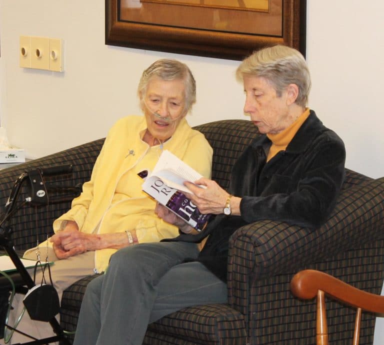 Sister Marietta Wethington, left, and Sister Maureen O’Neill discuss a book by Joyce Rupp while awaiting the retreat to begin again.