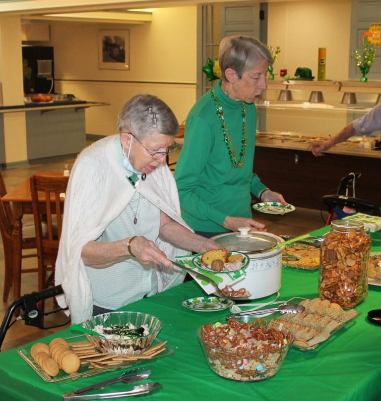 Sister Amanda Rose Mahoney, left, and Sister Maureen O’Neill gather some treats at the dining room party. Sister Amanda Rose said her father subscribed to a newspaper called Kentucky Irish Americans.