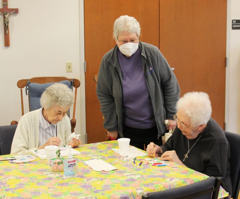 Sister Pat Lynch, standing, assistant congregational leader, stops by to admire the artwork of Sister Mary Gerald Payne, left, and Sister Mary Agnes VonderHaar.