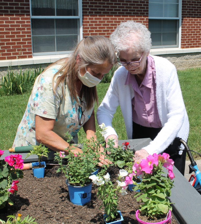 Sister Margaret Marie Greenwell, right, gets help from Terry Owen as she plants her flower.