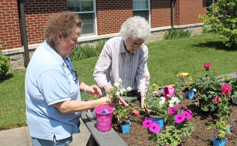 Sister Mary Gerald Payne, right, digs a hole for her plant, as Sister Alicia Coomes helps her. Sister Mary Gerald was looking forward to helping “dead head” the flowers this summer.