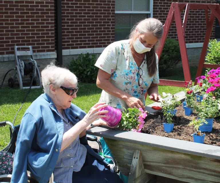 Sister Marie Goretti Browning, left, takes her wave petunia out of its container as she prepares to plant it, with help from Terry Owen.