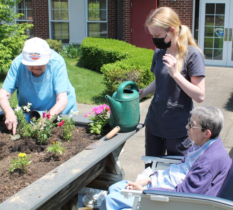 As Sister Catherine Kaufman digs in the dirt at left, nurse assistant Haley Larue prepares to water some plants as Sister Clarence Marie Luckett, right, looks on.