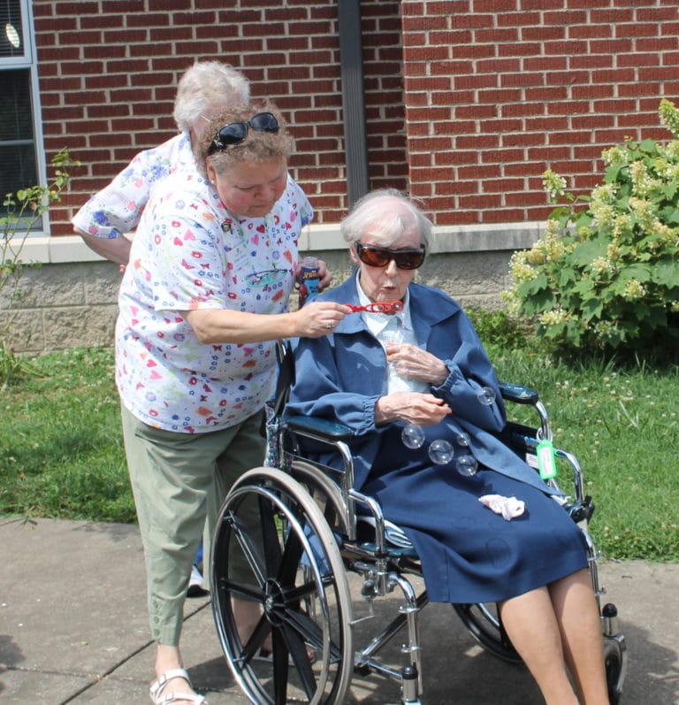 Sister Alicia Coomes, left, gets an assist as Sister Marie Goretti Browning blows her bubbles.