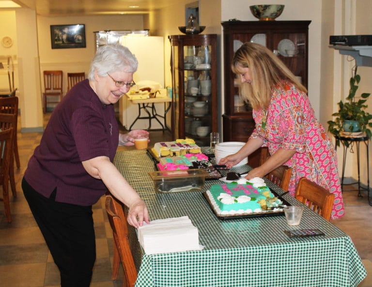Sister Pat Lynch, left, and Dee Dee Jackson, director of human resources, smile as Sister Pat gets ready for a piece of cake.