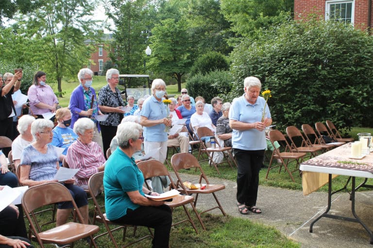 Sister Suzanne Sims, right, and Sister Angela Fitzpatrick also carry sunflowers, and behind them Sister Michele Morek and Sister Mary Timothy Bland bring bowls to the table.