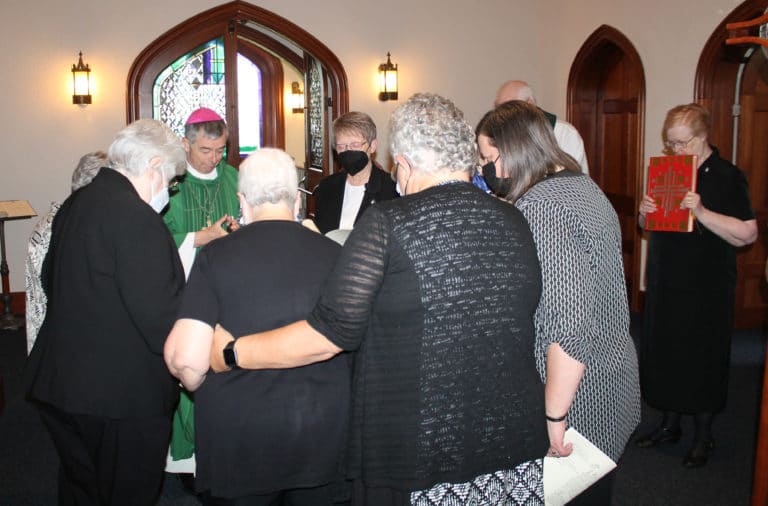 Bishop William Medley leads the outgoing and incoming Councils in prayer before the ceremony began. At right is Sister Helena Fischer, the first lector.