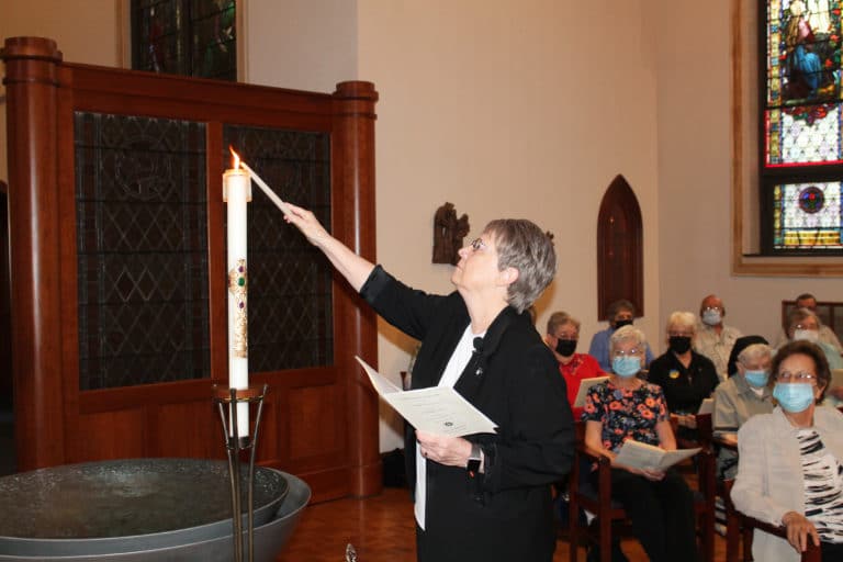 Sister Amelia Stenger, outgoing congregational leader, lights a taper from the Paschal Candle. She told the congregation, “The lit Paschal Candle symbolizes the light of Christ coming into the world. When this candle is lit during baptisms and religious professions, it signifies the Holy Spirit. Today, we will use its light to represent the guidance of the Holy Spirit passing from the current to the new leadership.”