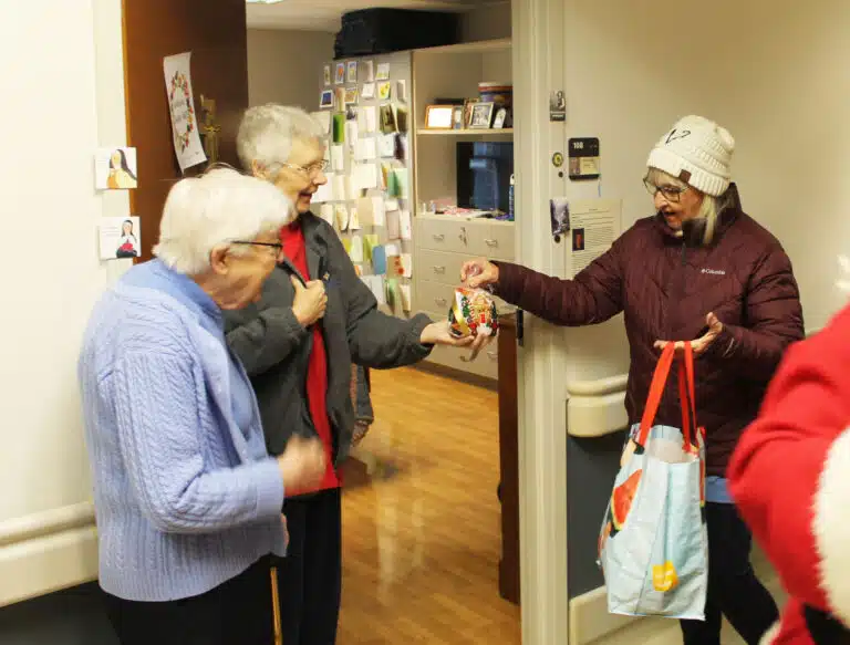 Sister Pat Lynch, center, receives a bag of candy from Mary Ann Willett, as Sister George Mary Hagan looks on.