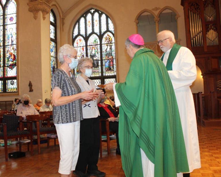 Sister Barbara Jean Head, left, and Sister Ann Patrice Cecil present the gifts to Bishop Medley and Father Ray Goetz.