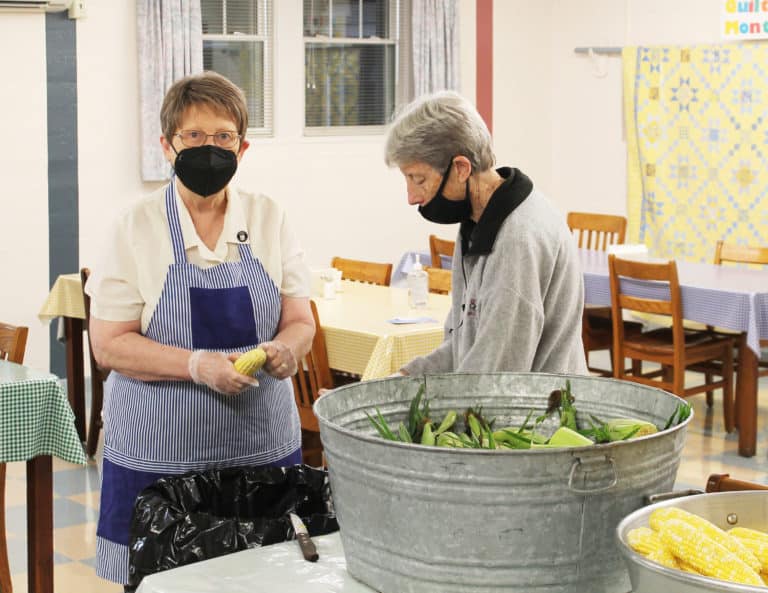 Sister Amelia Stenger, left, and Sister Maureen O’Neill strip the husks off the corn.