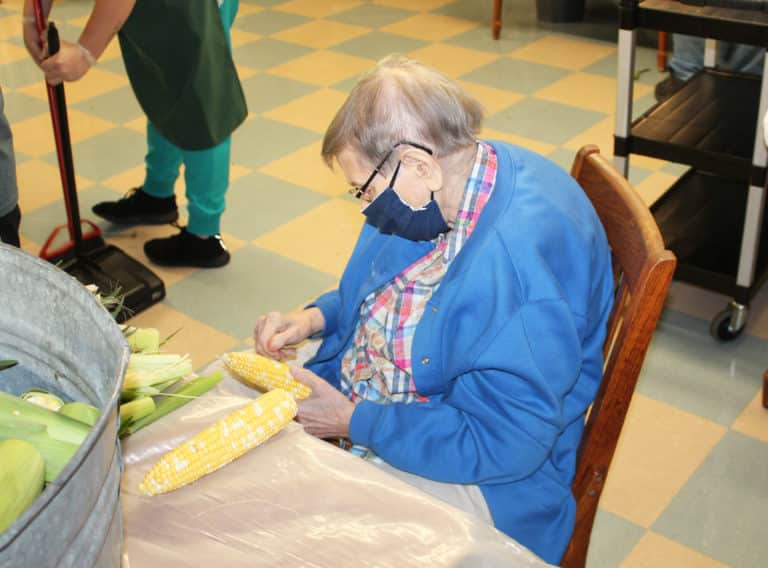 Sister Susanne Bauer takes the seated approach to cleaning the corn.