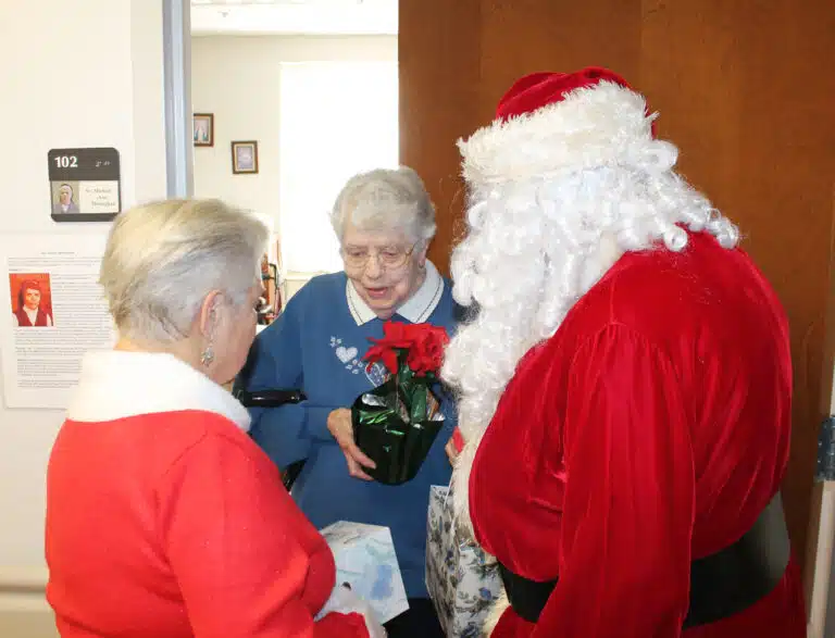 Sister Michael Ann Monaghan gratefully accepts her poinsettia and is eyeing the box of Puffs coming her way as well. Sister Michael Ann Monaghan gratefully accepts her poinsettia and is eyeing the box of Puffs coming her way as well.