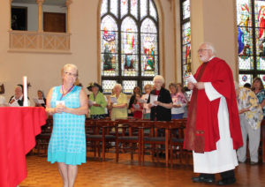 Sarah Olges Holden, A68, turns after placing the lectionary on the altar, as Father Ray Goetz, chaplain at Mount Saint Joseph, approaches the altar