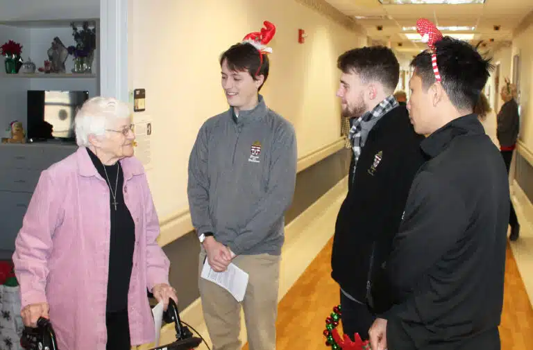 Sister Mary Matthias Ward chats with three seminarians who came to sing carols. From left are Ursuline Associate Wes Wheatley, Tommy Rhodes and Hoan Tran.