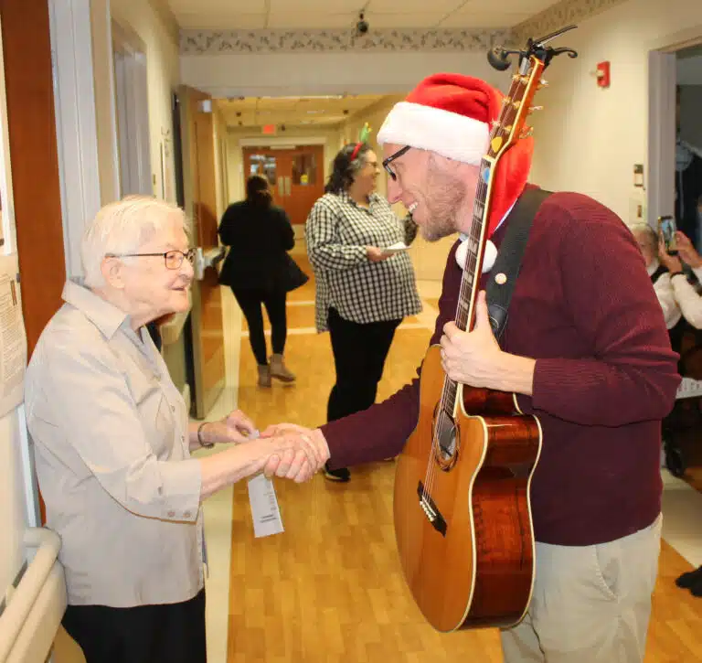 Danny May greets Sister George Mary Hagan after leading a chorus of Christmas carols.