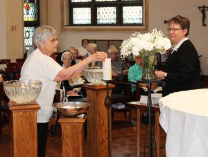 Sister Mary Celine Weidenbenner lights her candle as Sister Amelia looks on. Sister Mary Celine came to the Mount as a student in 1958.