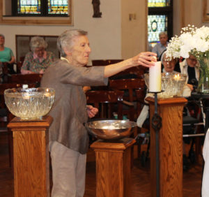 Sister Marietta Wethington lights her candle. She came to the Mount to enter the community in 1954.