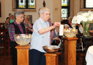 Sister Marie Montgomery lights her candle as Sister Nancy Murphy waits. Sister Marie came to the Mount as a Junior College student and joined the community in 1943.