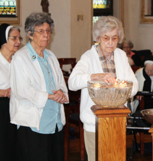 Sister Mary Gerald Payne places her candle in the water as Sister Luisa Bickett and Sister Rose Karen Johnson wait. Sister Mary Gerald joined as a postulant in 1952.