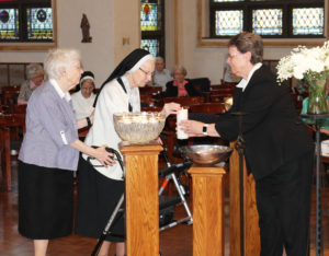 Sister Emerentia Wiesner receives assistance from Sister Amelia Stenger, right, and Sister Mary Irene Cecil to light her candle. Sister Emerentia has been an Ursuline Sister for 76 years, coming to the Mount from Paola, Kan., in 2009.