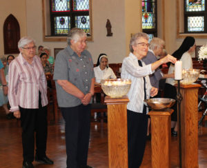 Sister Ann Patrice Cecil lights her candle as Sister Ruth Gehres and Sister George Mary Hagan wait. Sister Ruth and Sister George Mary did readings during the service.