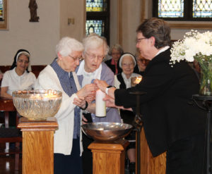 Sister Clarita Browning, left, gets assistance lighting her candle from Sister Mary Irene Cecil and Sister Amelia Stenger. Sister Clarita came to the Academy in 1943 and is celebrating 70 years as a sister this year.