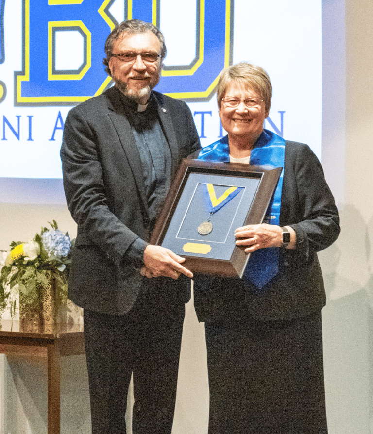 Sister Amelia Stenger receives her Distinguished Alumna Award from Brescia President Father Larry Hostetter.