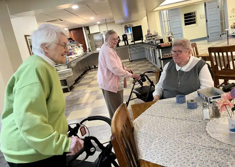 Ursuline Sister Mary Matthias Ward, left, and Ursuline Sister Marie Joseph Coomes, center, are greeted by Glenmary Sister Pat Leighton as they enter the dining room. Ursuline Sister Mary Matthias Ward, left, and Ursuline Sister Marie Joseph Coomes, center, are greeted by Glenmary Sister Pat Leighton as they enter the dining room.