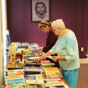 Associates Brenda Busick, left, of Greenville, Ky., and Mary Hartz of Owensboro look over the table of free books prior to the start of Associates and Sisters Day.