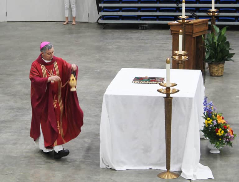 Bishop William Medley uses a censer to bless the makeshift altar in the Sportscenter.