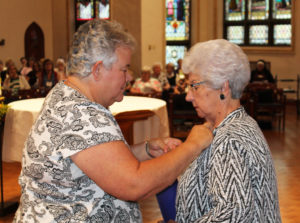 Sister Martha Keller puts the associate pin on her sister-in-law, Joy Keller.