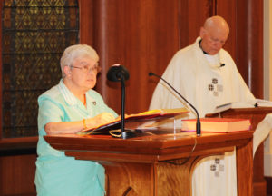 Sister Cecelia Joseph Olinger reads the intercessions, as Father Joe Merkt listens in the background.