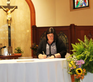 Sister Stephany signs her formula of profession on the altar.