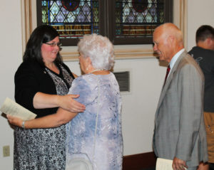 Sister Stephany gets a hug following Mass from her godmother Lyn Knepler, as her godfather John Knepler smiles.