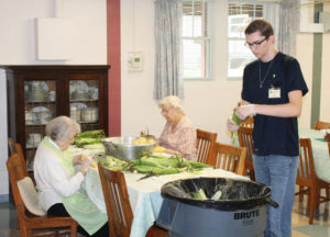 Ursuline Sisters Alfreda Malone, left, and Eva Boone cut the corn that has been shucked by food service aide Ben Duncan in the small dining room.