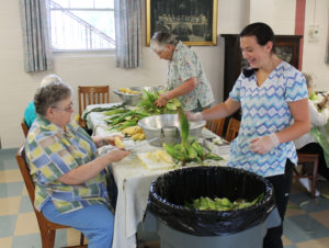Food service assistant Abby Smith, right, smiles as she works with Sister Joyce Marie Cecil on the corn.