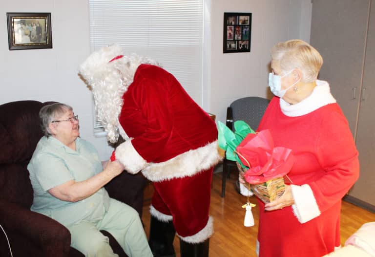 Sister Joyce Marie Cecil was excited to greet Santa, as Mrs. Claus prepares to give her a present.