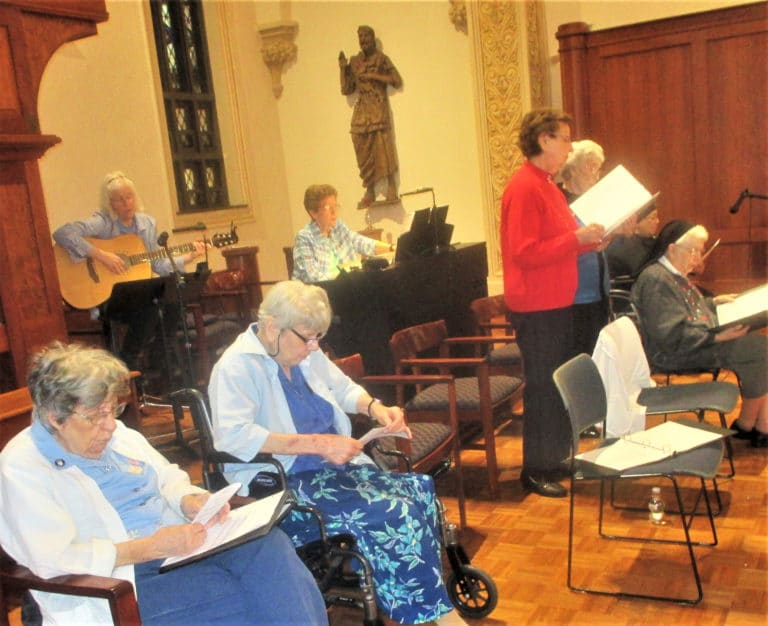 The small choir of Sisters sings songs in Spanish during the Mass, as Sister Nancy Liddy accompanies on guitar and Sister Mary Henning plays the piano. Each of the Sisters in the choir has experience ministering to Hispanic people. From left are Sister Luisa Bickett, who served 59 years in New Mexico, Chile and to Hispanics in Ohio County; Sister Sheila Anne Smith, a New Mexico native who served 35 years in New Mexico and Arizona; Sister Susan Mary Mudd, who along with Sister Luisa was one of the original Sisters to serve in South America; Sister Elaine Burke, who spent eight years serving in New Mexico; Sister Michael Ann Monaghan (seated right), who served 28 years in New Mexico; and Sister Sara Marie Gomez, a New Mexico native who served 29 years in New Mexico. Also in the choir, but not pictured, was Sister Ruth Gehres, who served six years in Chile.