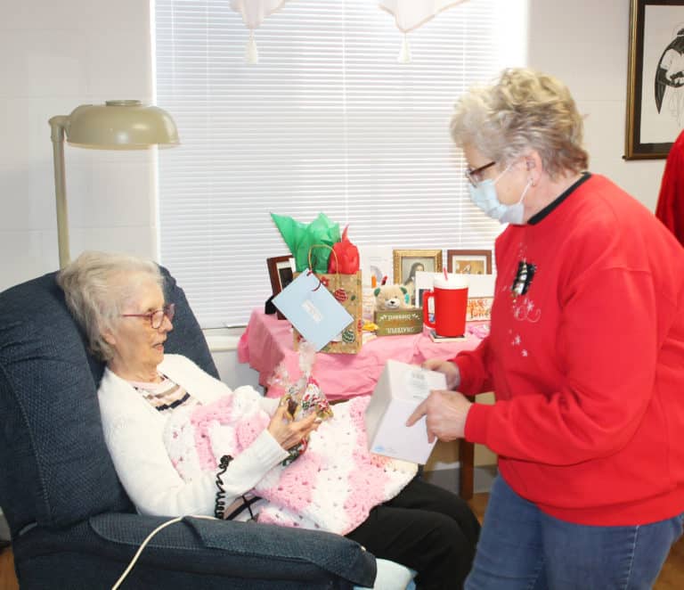Lois Bell brings a bag of candy and cookies to Sister Margaret Marie Greenwell, followed by some more gifts. Sister Margaret Marie served in Paducah from 1967-85.