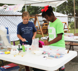 Two patrons of the Kids Tent practice their “splattering” to make a craft project.