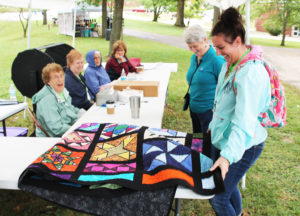 Maggie Matsko, right, communications specialist for the Ursuline Sisters, laughs as she spreads out the quilt that was raffled off in the grand raffle. Clara Nall, of Brandenburg, Ky., won the quilt. Sister Pam Mueller is next to Maggie, and those seated from left are Sister Elaine Burke, Sister Helena Fischer, Sister Barbara Jean Head and Sherri Heckel.