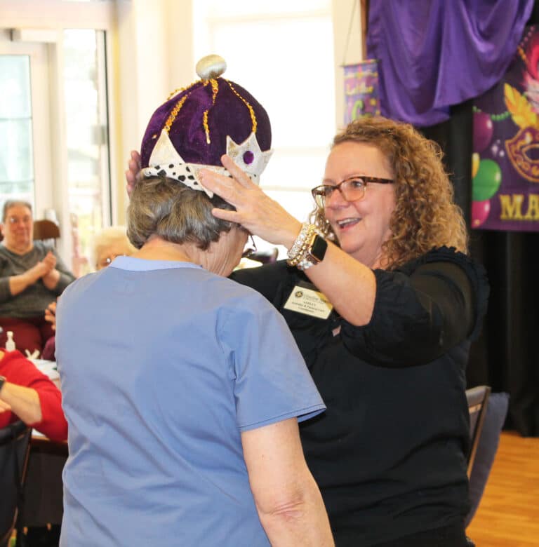 Although there was no baby to find in a king cake, Ashley Wilkerson, right, activities and pastoral care coordinator in Saint Joseph Villa, crowns Sister Jacinta as “Mardi Gras queen.” Although there was no baby to find in a king cake, Ashley Wilkerson, right, activities and pastoral care coordinator in Saint Joseph Villa, crowns Sister Jacinta as “Mardi Gras queen.”