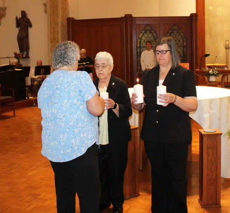 Sister Martha Keller lights four candles, two each held by outgoing Council members Sister Monica Seaton, right, and Sister Ann McGrew. Sister Martha Keller lights four candles, two each held by outgoing Council members Sister Monica Seaton, right, and Sister Ann McGrew.